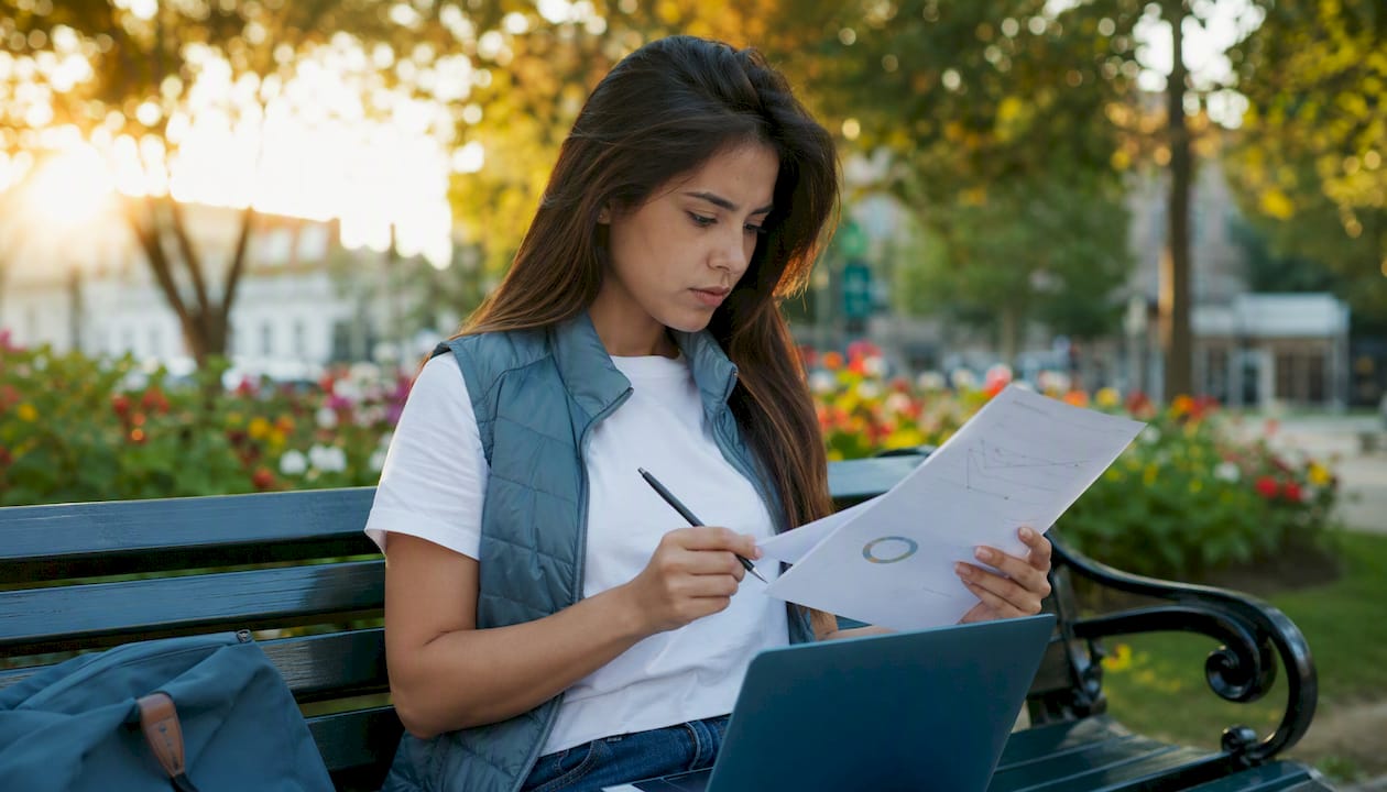 Manos escribiendo en un teclado junto a copias impresas de correos electrónicos fraudulentos.
